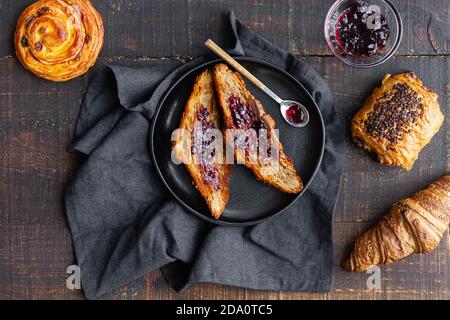 Vue de dessus de délicieux croissants faits maison avec de la confiture de cerises douces disposés sur une table en bois avec un délicieux petit pain au chocolat et rouler avec du raisin Banque D'Images