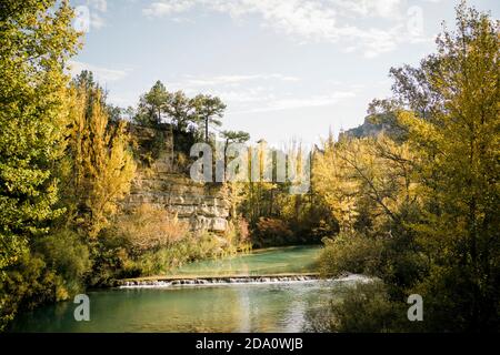 Vue panoramique sur la petite rivière avec chute d'eau qui coule à travers la montagne terrain couvert d'une forêt colorée en automne ensoleillé Banque D'Images