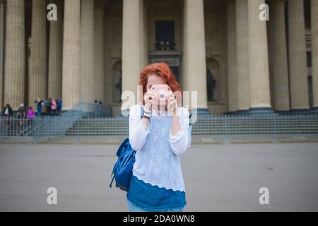 Jeune touriste femelle aux cheveux rouges avec sac à dos photo avec Caméra instantanée en vous tenant contre la célèbre cathédrale de Kazan en été Jour à Saint Banque D'Images