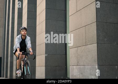 Femme coursier à vélo près du grand bâtiment de la ville l'été jour Banque D'Images