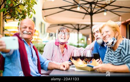 Couples seniors prenant le selfie au bar du restaurant avec masques faciaux - Nouveau concept de style de vie normal avec des gens heureux ayant le plaisir ensemble à l'extérieur, en mode covid- Banque D'Images