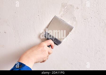 Mur de plâtrage par travailleur avec spatule de peintre et stuc pendant les réparations à plat. Banque D'Images