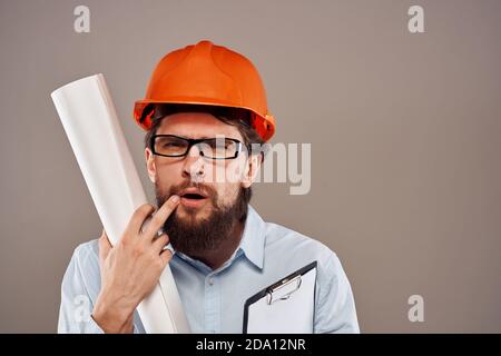 Homme ingénieur avec des lunettes de peinture orange. Des plans professionnels entre les mains Banque D'Images