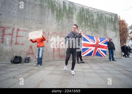 Manchester 08-11-2020, un homme danse devant un mur avec des graffitis « le Nord n'est pas un plat de pétri » lors de la manifestation anti-verrouillage du 8 novembre 2020 Banque D'Images