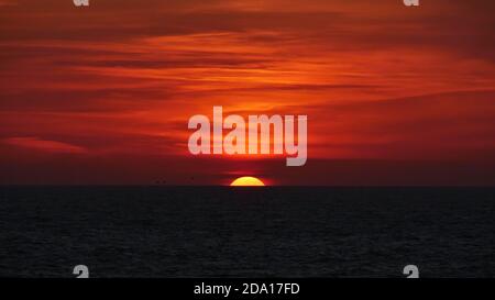 Coucher de soleil majestueux avec ciel spectaculaire, nuages orange et rouge et soleil en voie de disparition à l'horizon de l'océan Atlantique sur la côte d'Essaouira. Banque D'Images