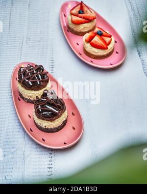 Assiettes décoratives de gâteaux au chocolat et aux fraises à travers flou plantes Banque D'Images