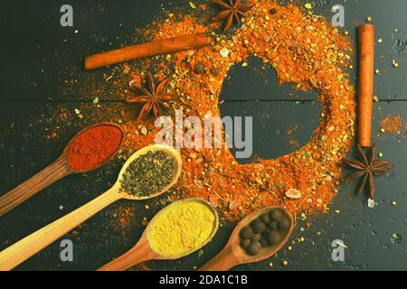 Ensemble d'épices sur fond gris foncé. Cuillères à bois avec paprika, curcuma, herbes et poivre à la cannelle et à l'anis. Composition du condiment en forme de coeur. Cuisine et saveurs Banque D'Images