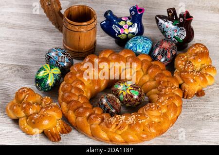 Pain fait maison tressé d'Europe de l'est avec des œufs peints traditionnels isolés sur une table en bois. Banque D'Images