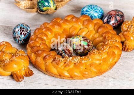 Pain fait maison tressé d'Europe de l'est avec des œufs peints traditionnels isolés sur une table en bois. Banque D'Images