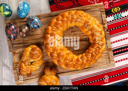 Pain fait maison tressé d'Europe de l'est avec des œufs peints traditionnels isolés sur une table en bois. Banque D'Images