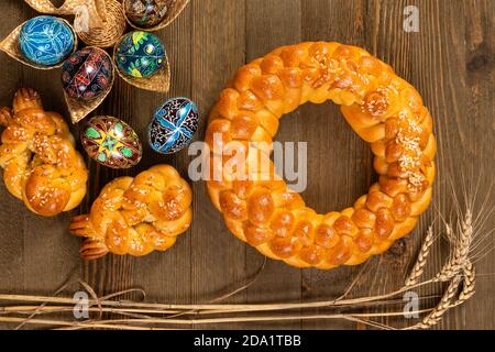 Pain fait maison tressé d'Europe de l'est avec des œufs peints traditionnels isolés sur une table en bois. Banque D'Images