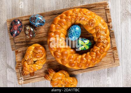 Pain fait maison tressé d'Europe de l'est avec des œufs peints traditionnels isolés sur une table en bois. Banque D'Images