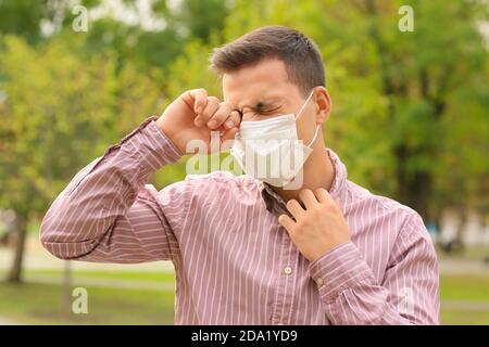 Jeune homme en masque médical souffrant d'allergies en plein air Banque D'Images