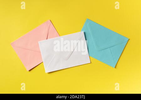 Trois enveloppes de couleurs différentes, prises par le haut sur fond jaune Banque D'Images