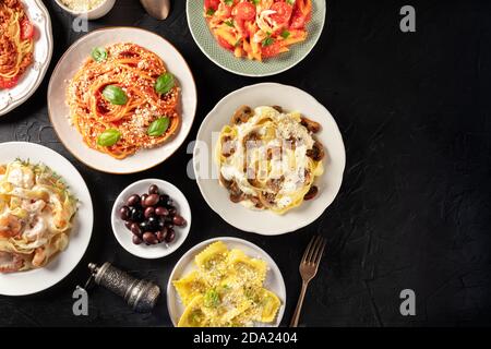 Pâtes italiennes, plats variés, avec viande, poulet, légumes, champignons, fruits de mer, tiré du dessus sur fond noir avec un lieu pour le texte Banque D'Images