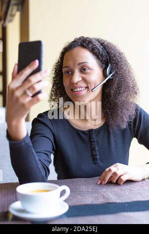 Photo verticale d'une femme africaine avec micro-casque/oreillette ayant un appel vidéo. Gros plan. Image verticale. Banque D'Images