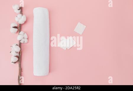 Vue de dessus des serviettes roulées de fleurs de coton et des tampons de coton isolés sur fond rose Banque D'Images