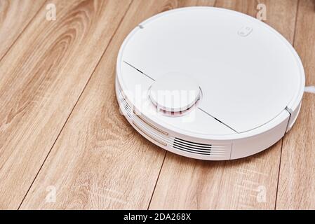 Robot-aspirateur fonctionnant sur sol stratifié. Technologie domestique avec télécommande Banque D'Images