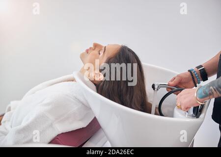 Mains mâles tenant la pomme de douche avec l'eau courante Banque D'Images