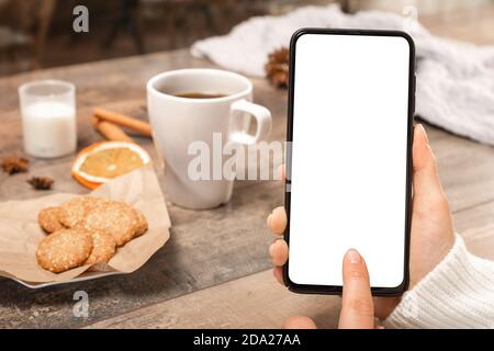 Mockup image vierge écran blanc téléphone cellulaire. Femme main tenant le SMS à l'aide d'un mobile sur le bureau au café. Téléphone portable avec main, blanc Banque D'Images