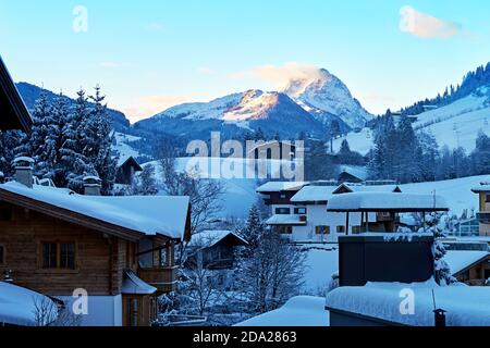 Village alpin d'hiver sur la pente enneigée à l'ombre de la montagne. Stations de ski et destinations de voyage Banque D'Images