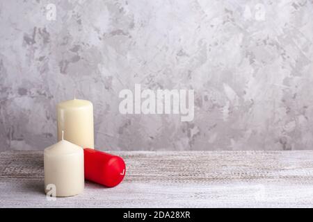 composition de trois bougies vanille et rouge sur une table en bois sur fond gris, espace de copie pour le texte Banque D'Images