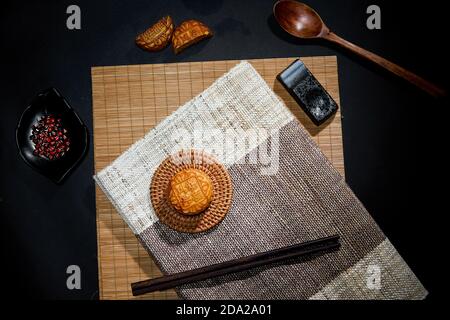 Vue de dessus du gâteau de lune avec des baguettes sur un tapis une surface sombre Banque D'Images