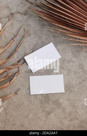 Maquettes de cartes de visite blanches et feuilles de palmier brunes sèches sur fond de table texturé. Modèle moderne élégant pour l'identité de marque. Tropical Banque D'Images