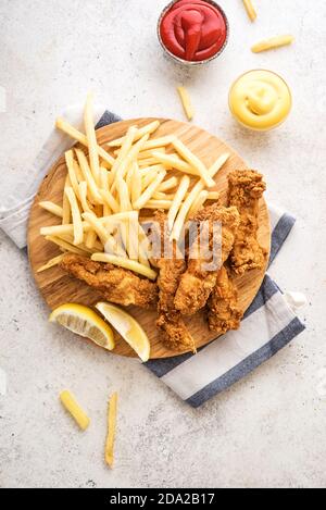 Poisson et frites. Filet de poisson frits et frites sur fond blanc avec sauces. Cuisine de rue britannique traditionnelle, vue sur le dessus, espace copie. Banque D'Images