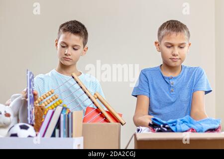 Les enfants bénévoles trient des jouets, des vêtements, des livres, des produits de don dans des boîtes de dons de charité à l'intérieur Banque D'Images