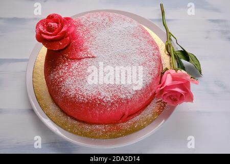 Gâteau rouge recouvert de marzepan ou de mastic avec une fleur, fond blanc Banque D'Images