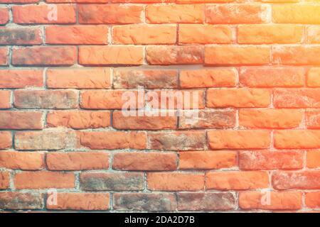 Arrière-plan rétro gaspillant loin du brickwork, gros plan. Le mur de briques texturé est rouge et gris. Arrière-plan de vieux mur de brique usé, rayons de soleil. Banque D'Images