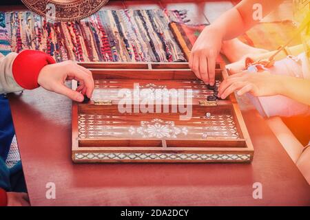 Deux joueurs s'assoient en face et jouent à un jeu de société de backgammon. Mains les jetons pour jouer le jeu dans le backgammon vintage. Banque D'Images