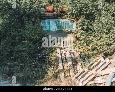 Vieux fer abandonné camion soviétique densément surcultivé avec des buissons verts et empilé haut avec des palettes d'entrepôt Banque D'Images