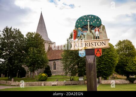 Royaume-Uni, Angleterre, East Sussex, Alfriston, peint un panneau de village en bois sur vert près de l’église St Andrew Banque D'Images