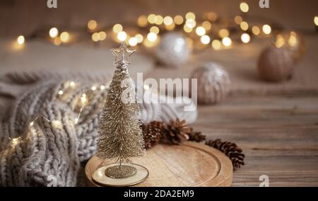 Petit sapin de Noël décoratif brillant gros plan sur un fond de lumières floues avec bokeh dans des couleurs chaudes. Banque D'Images