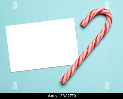 Carte de vœux de Noël avec canne en sucre sur fond bleu pastel. Zone vide isolée avec un masque. Banque D'Images