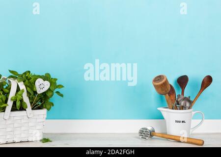 Cuisine avec une variété d'ustensiles de cuisine vintage verre mesureur et plante de basilic dans le panier blanc à l'avant de mur couleur aqua Banque D'Images