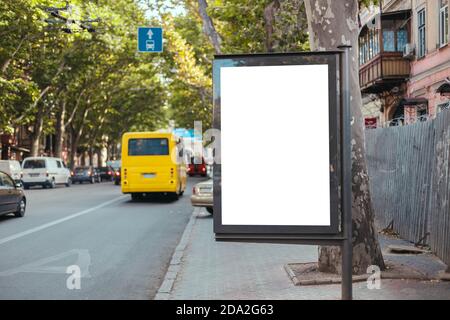 Maquette vierge avec panneau d'affichage vertical dans une rue très fréquentée. Le bus jaune circule sur une ligne dédiée dans la ville Banque D'Images