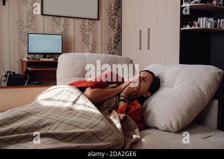 Femme malade et grippe. Pris au froid. Femme se sentant froide avec une couverture reposant sur le canapé à la maison Banque D'Images