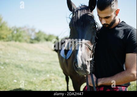 Homme arabe grande barbe porter en noir avec le cheval arabe. Banque D'Images