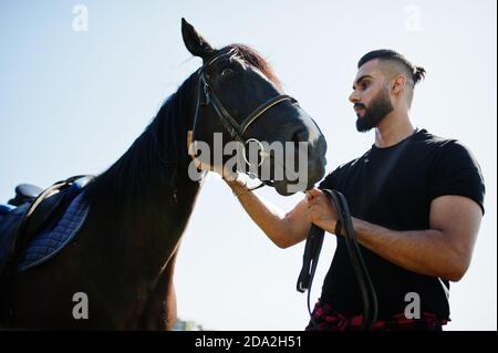 Homme arabe grande barbe porter en noir avec le cheval arabe. Banque D'Images