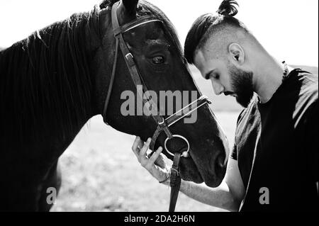 Homme arabe grande barbe porter en noir avec le cheval arabe. Banque D'Images