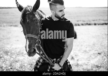 Homme arabe grande barbe porter en noir avec le cheval arabe. Banque D'Images