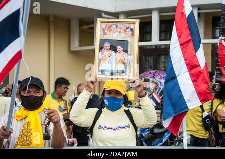 Une femme royaliste thaïlandaise portant un masque tient un portrait de la famille royale thaïlandaise pendant la manifestation. Les partisans royalistes thaïlandais du roi Maha Vajiralongkorn protestent pour exiger la protection de la monarchie tandis que les manifestants pro-démocratie se réunissent au Monument de la démocratie. Banque D'Images