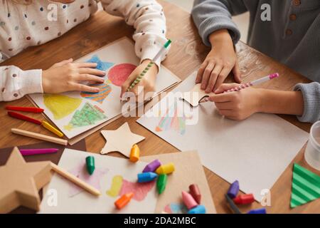 Gros plan grand angle des enfants traçant des formes tout en dessinant des cartes de Noël à l'école, espace de copie Banque D'Images