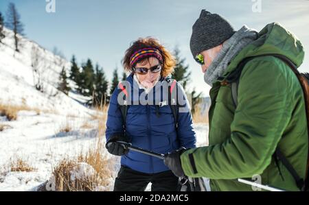 Randonneurs en couple senior avec des bâtons de marche nordique dans la neige-couvert nature d'hiver, au repos. Banque D'Images