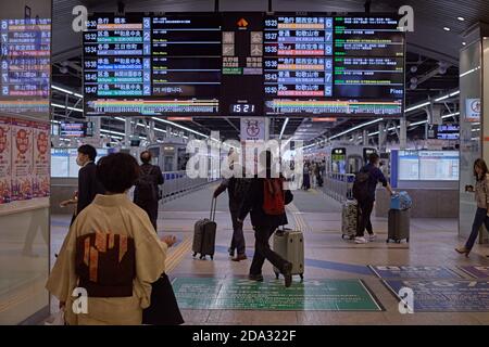 Osaka, Japon, avril 2018. Personnes transportant des valises sous le panneau lumineux informatif à la gare de Namba. Banque D'Images