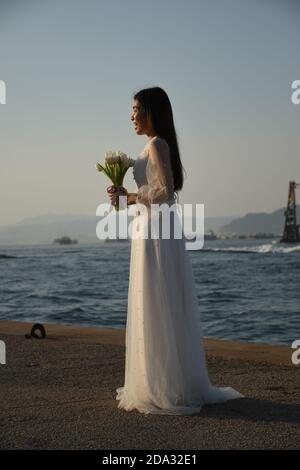 Fille asiatique vêtue comme mariée prenant la photo à Sai WAN Quai de fret (également appelé quai Instagram) à Hong Kong Banque D'Images