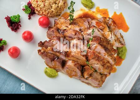 Steak grillé avec sauce et pilaf de bulgur sur une table en bois. Banque D'Images